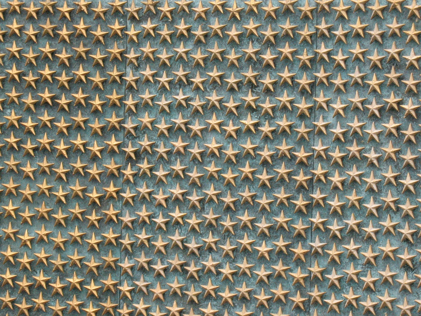 A photo of the WWII memorial in D.C. It shows many gold stars against a green-grey background.