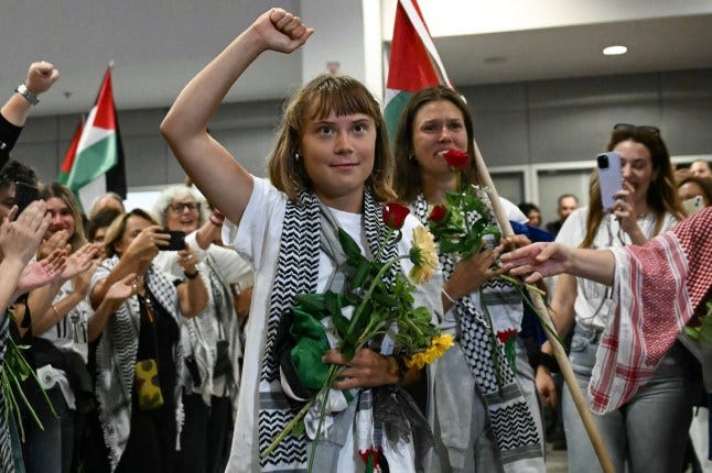Swedish climate campaigner Greta Thunberg raises her fist, upon arrival alongside activists who were sailing aboard vessels from the Gaza-bound aid flotilla before being stopped and detained by Israeli forces, greeted by a crowd of supporters, at the arrivals area of Athens International Airport on October 6, 2025. Greece's foreign ministry said 161 nationals from 16 European countries landed in Athens on Ocotber 6, 2025, after being expelled by Israel for taking part in a Gaza aid flotilla. Israel on Monday deported more activists who were on the flotilla bound for the devastated Palestinian territory, including Swedish climate campaigner Greta Thunberg. The 45-vessel flotilla had been aiming to break an Israeli blockade to deliver aid to Gaza, where the United Nations says famine has taken hold after two years of devastating conflict (Photo by Aris MESSINIS / AFP) (Photo by ARIS MESSINIS/AFP via Getty Images)
