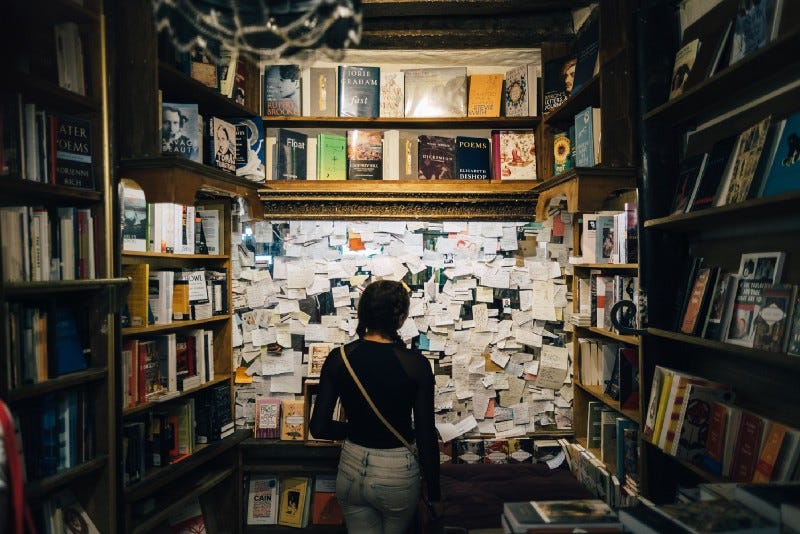 A woman looking at a board full of post-its in a library A woman looking at a board full of post-its in a library