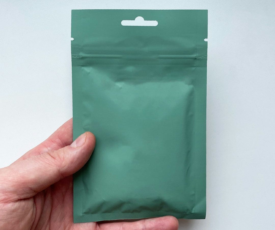 A hand holds a blank green stand-up pouch. A hand holds a blank green stand-up pouch.