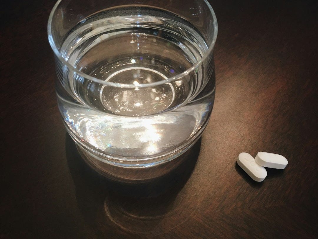 two oval white medication tablets on brown surface two oval white medication tablets on brown surface