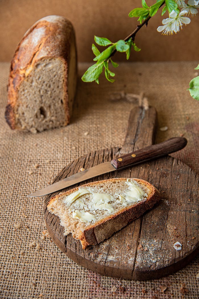 A slice of buttered bread next to a knife. A slice of buttered bread next to a knife.