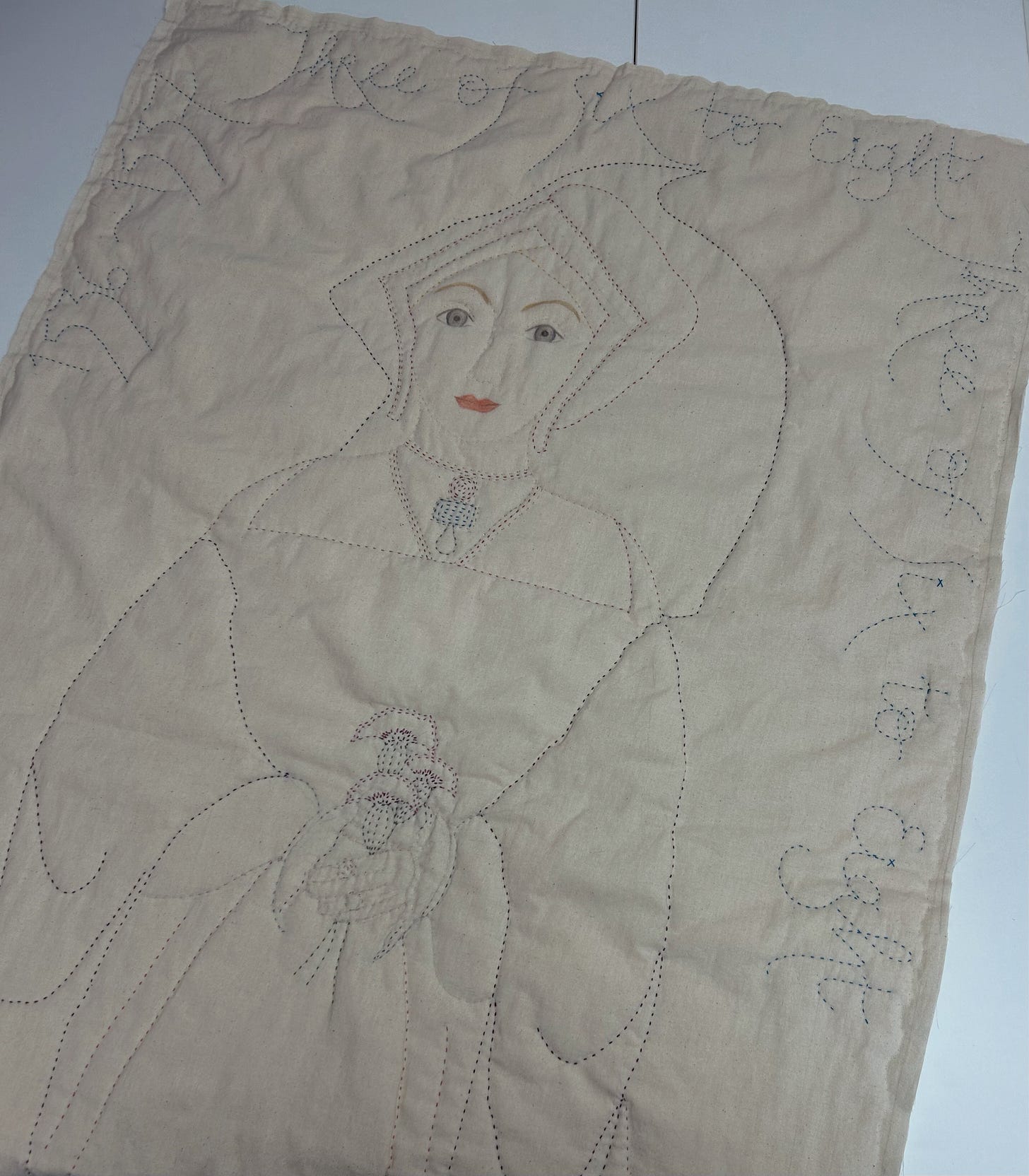 Cream quilted calico figure of a Tudor woman wearing a gable hood and holding three carnations. Around the edge of the piece are the words “Three of Six to Eight” and the dates 1536-1537. Cream quilted calico figure of a Tudor woman wearing a gable hood and holding three carnations. Around the edge of the piece are the words “Three of Six to Eight” and the dates 1536-1537.