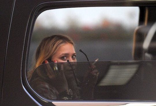 This may contain: a woman talking on her cell phone while sitting in a vehicle with the door open