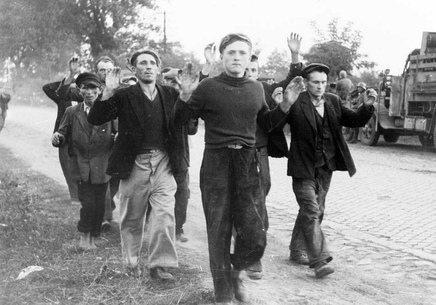 Defenseless Polish civilians, arms raised, walk along a road as prisoners of war during the German invasion in September 1939. Defenseless Polish civilians, arms raised, walk along a road as prisoners of war during the German invasion in September 1939.
