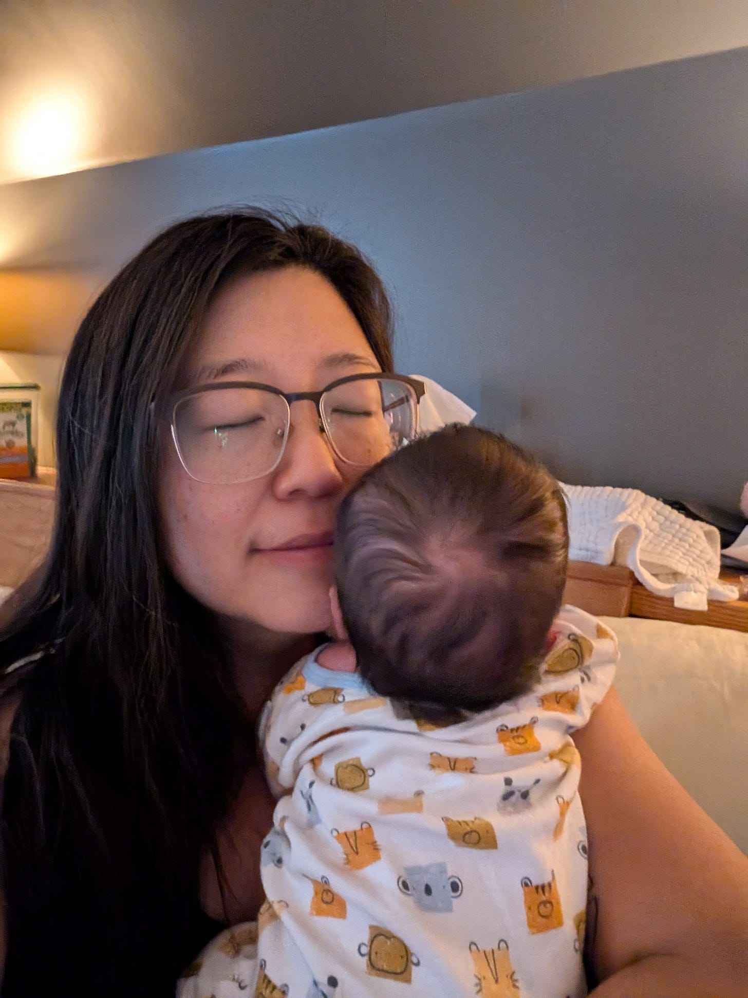 Picture of a woman with her eyes closed holding a newborn baby to her face