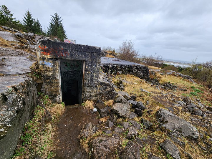 A concrete doorway into the hillside, and an open door leading straight down steps into an underground bunker.