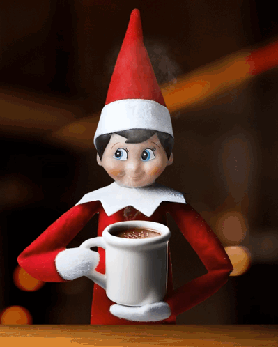 an elf on the shelf is holding a mug of hot chocolate