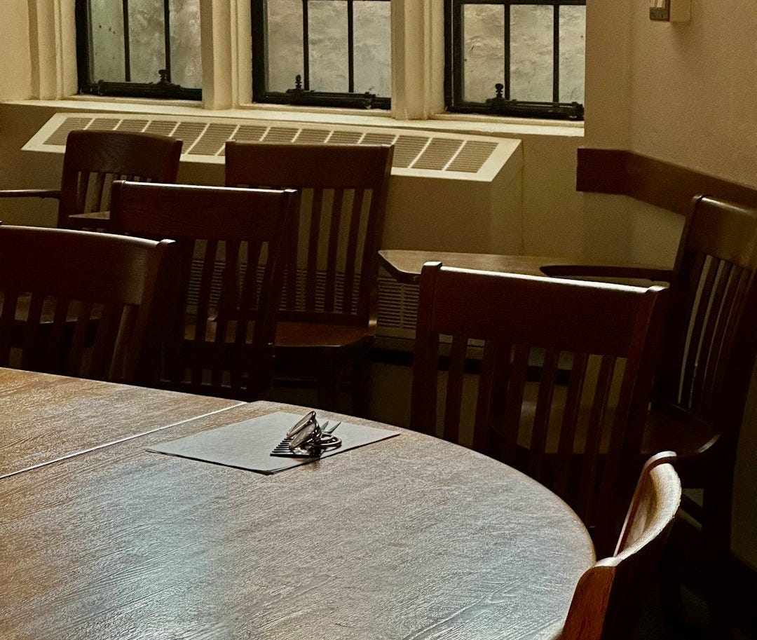 Empty classroom with wooden chairs and table.