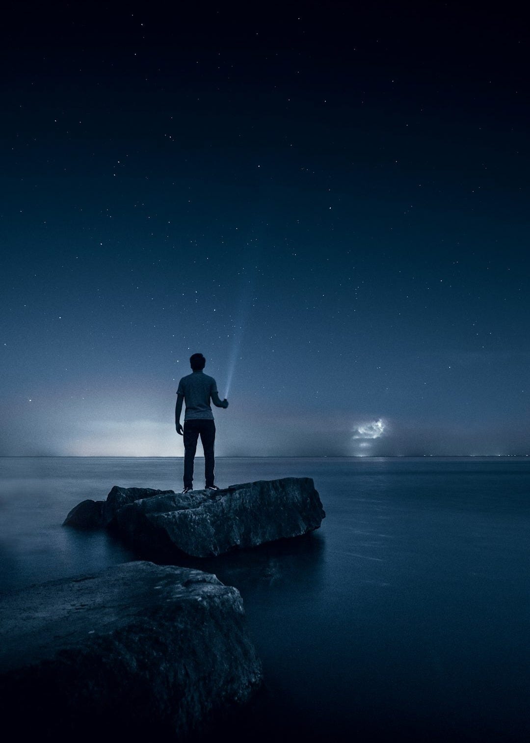 man holding flashlight standing on rock