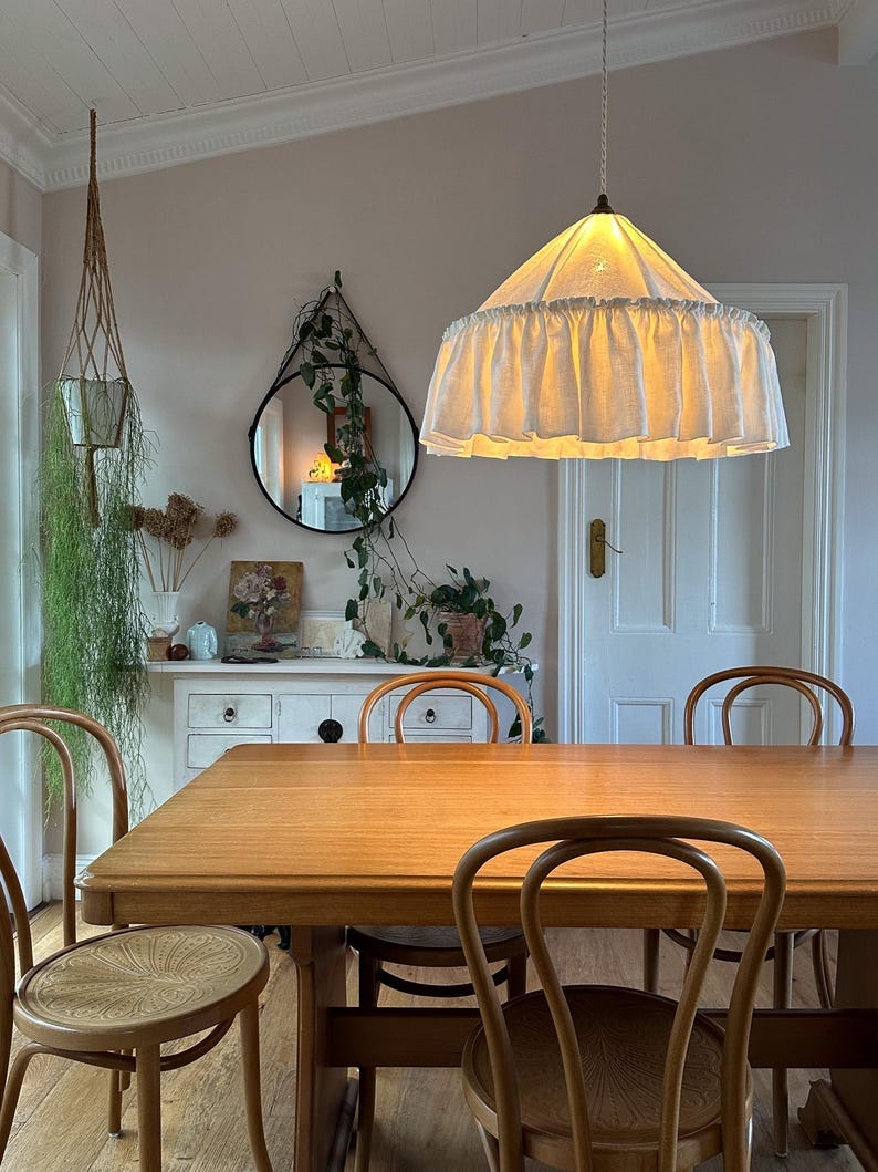ivory linen large rufffle light shade with warm glow, hanging above vintage dining able and bentwood chairs