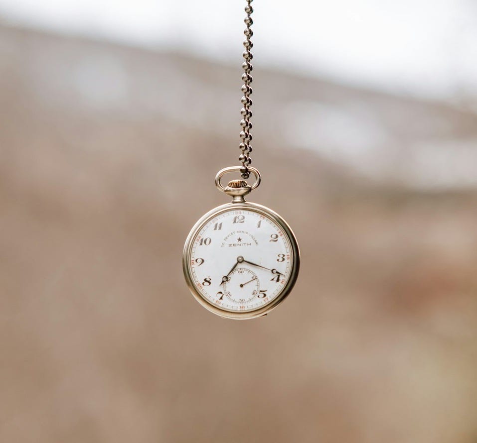 a person holding a small pocket watch in their hand