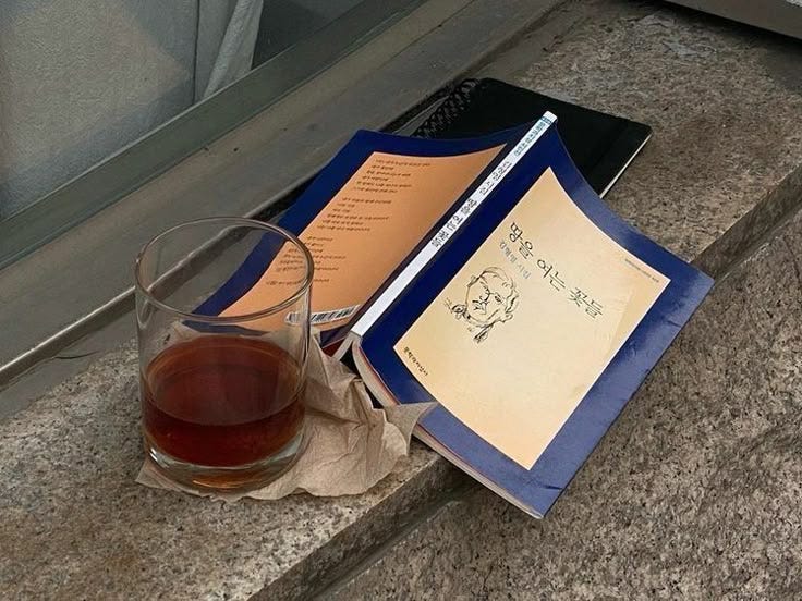 This may contain: an open book next to a glass of wine