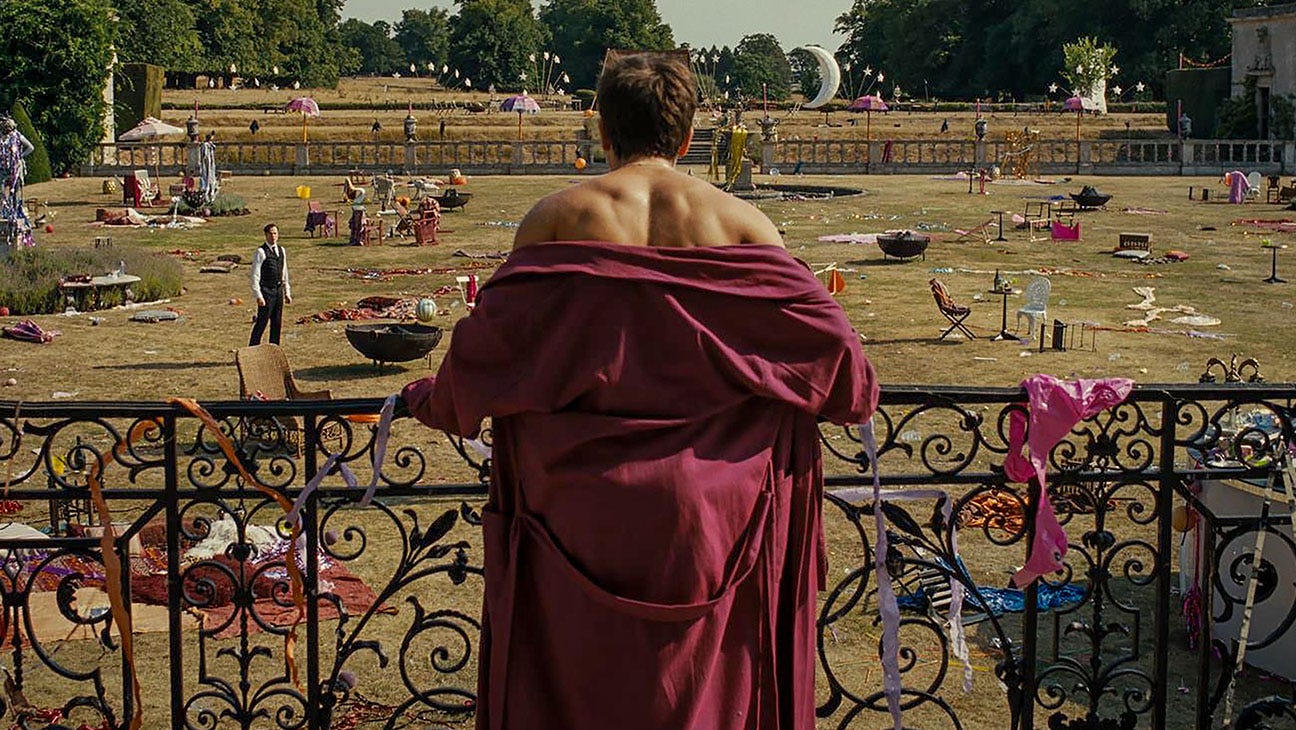 Oliver (Barry Keoghan) standing at a railing looking at the remains of a party on a massive lawn