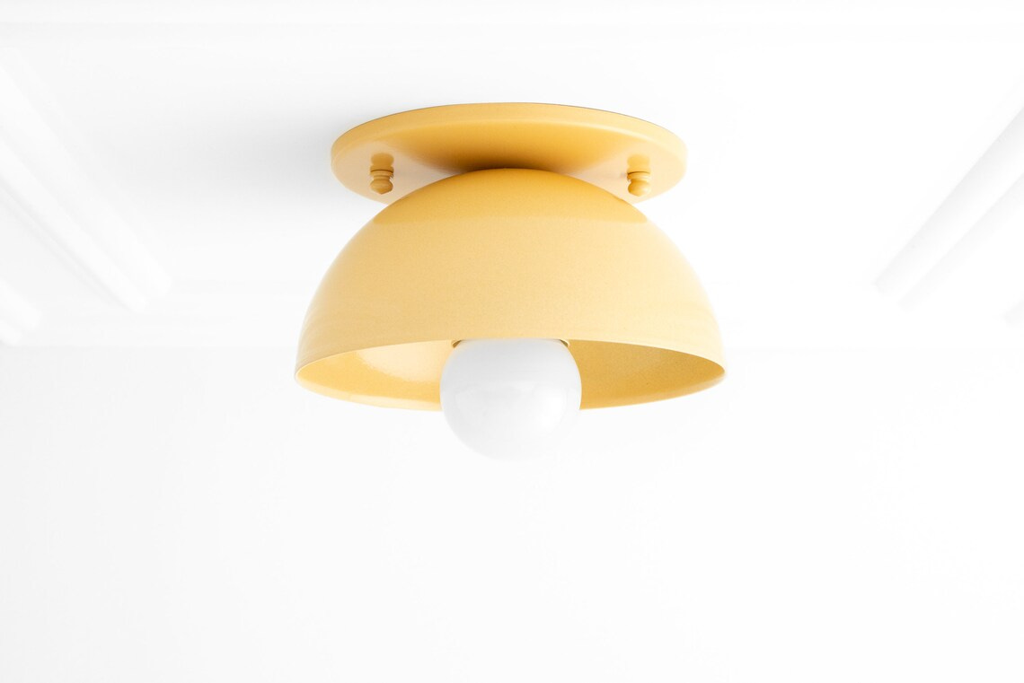 May include: A yellow dome-shaped ceiling light fixture with a white light bulb. May include: A yellow dome-shaped ceiling light fixture with a white light bulb.