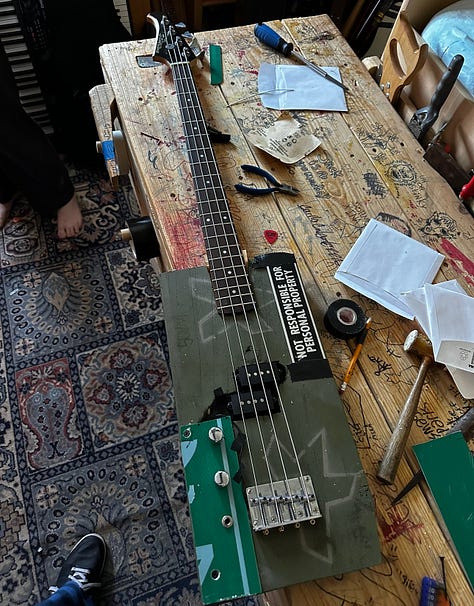 A guitar made out of a lunchbox and a broken guitar neck, a bass made out of a surplus military box, and a drum set made out of, basically, trash