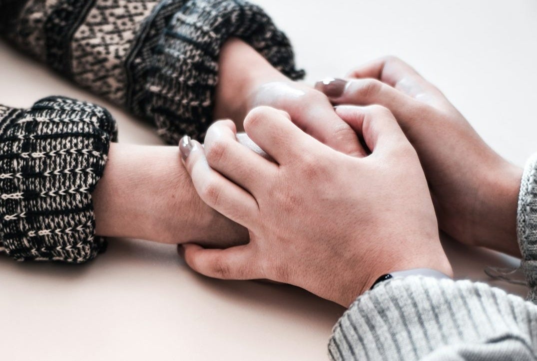 person in gray long sleeve shirt holding persons hand
