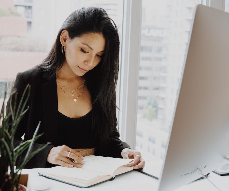 Lady reading her journal in front of computer