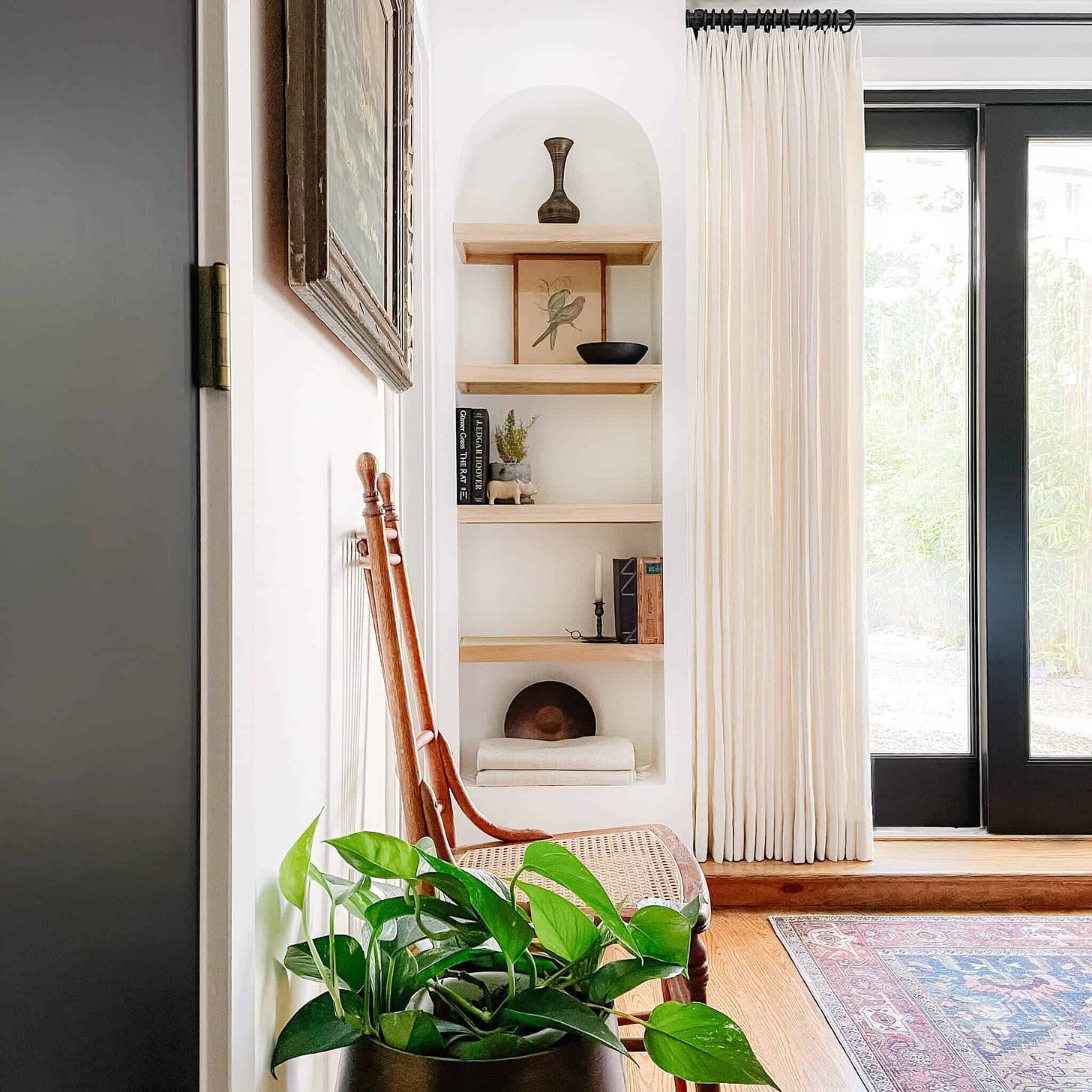 Interior design by Anthony from 135 home with a green pothos plant in front. a vintage chair and arched bookcase. Interior design by Anthony from 135 home with a green pothos plant in front. a vintage chair and arched bookcase.