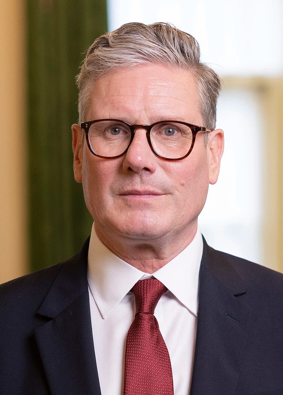 official portrait of Kier Starmer, with glasses, looking startled official portrait of Kier Starmer, with glasses, looking startled