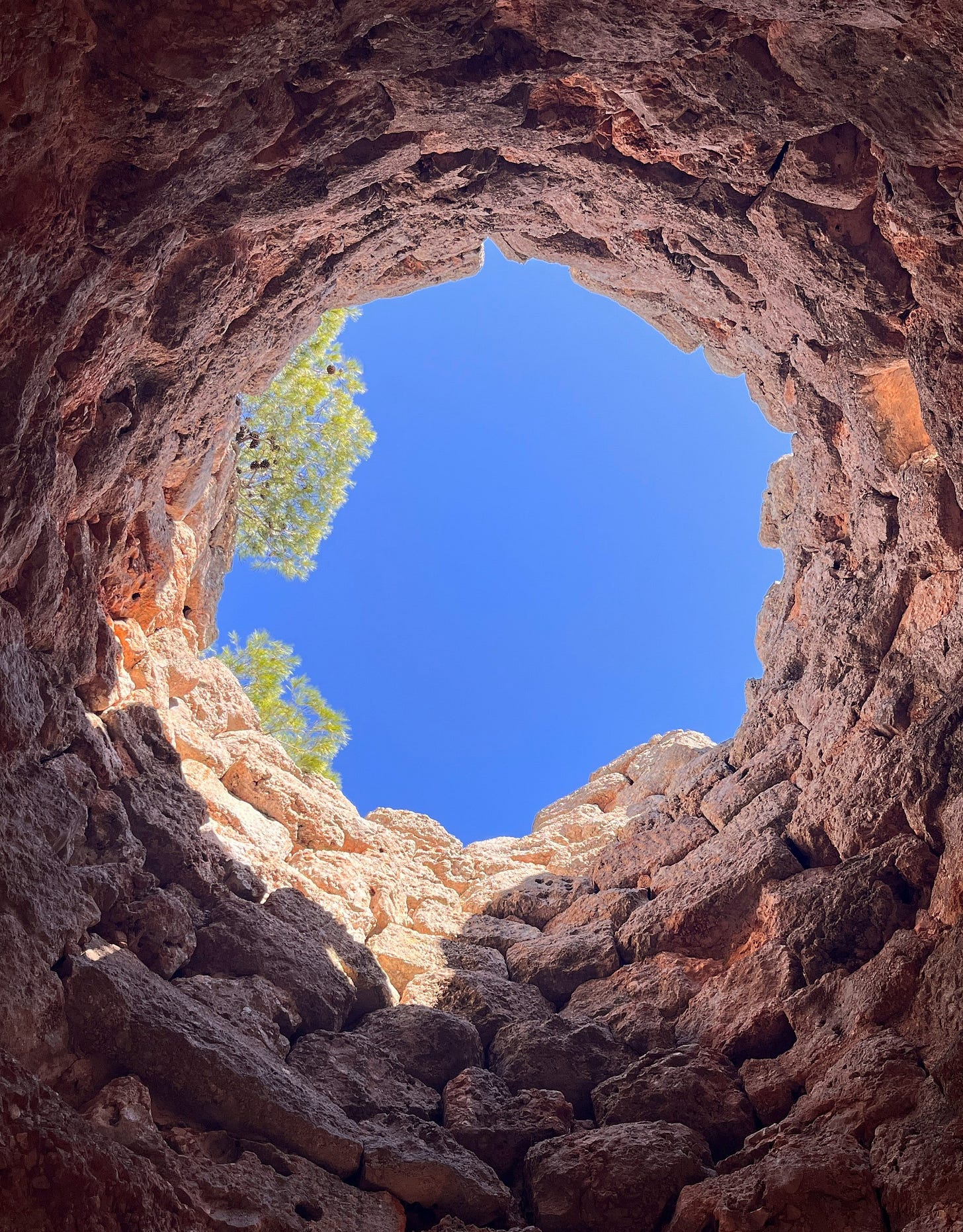 Looking up from a deep rocky hole with blue sky above