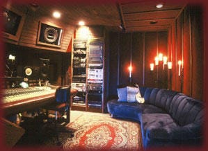 A photo of a recording studio with a rug and blue couch behind the large soundboard A photo of a recording studio with a rug and blue couch behind the large soundboard