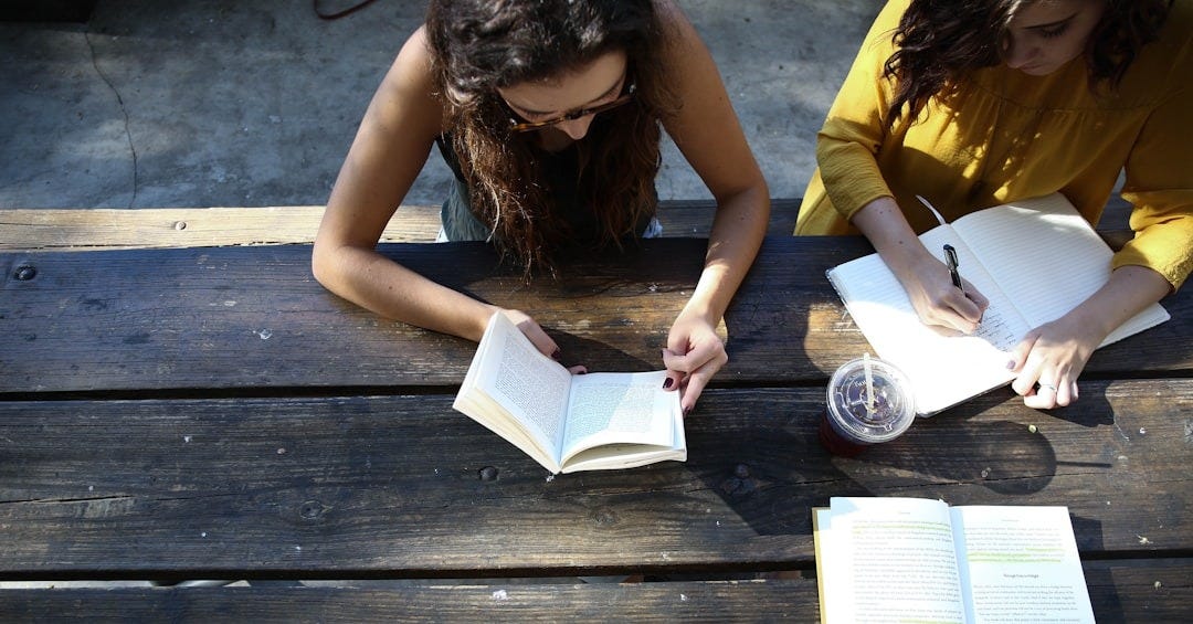 woman reading book while sitting on chair