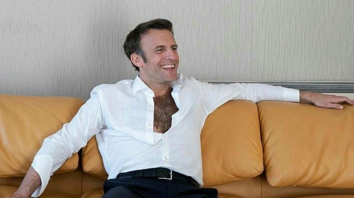 Emmanuel Macron lounges on a sofa, his shirt unbuttoned most of the way down to reveal a surprisingly hairy chest
