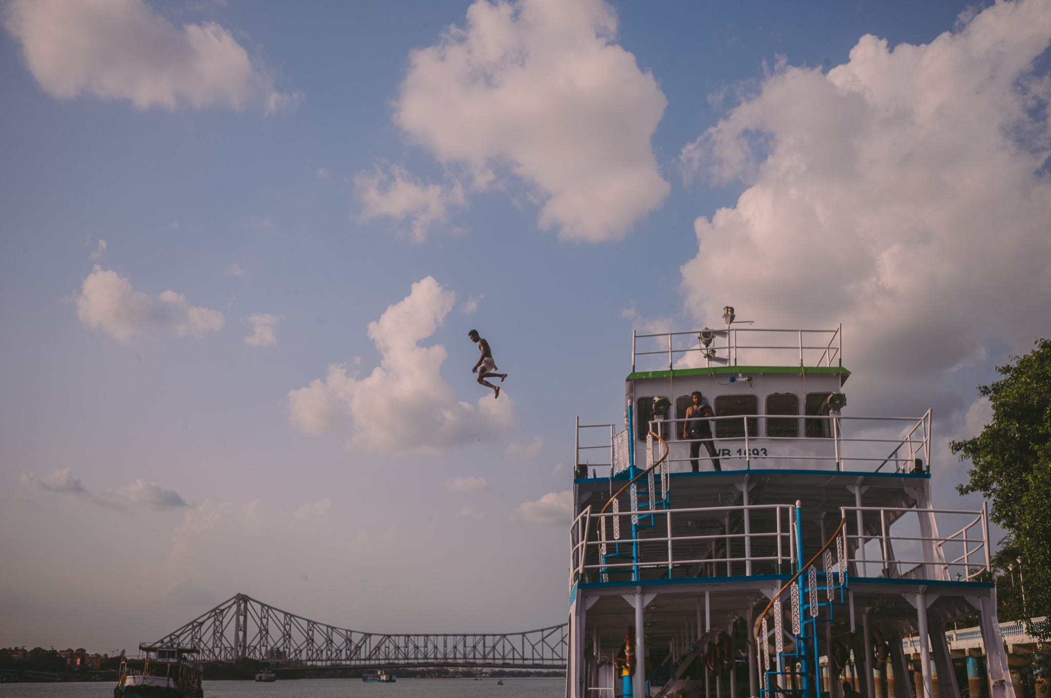 The boys were jumping into the water from the dock while I photographed them. Suddenly, he asked me to follow him, climbed onto a big parked boat, and jumped from there.