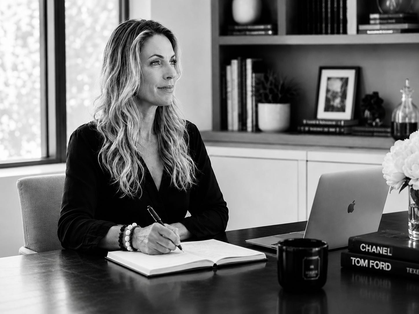 Black-and-white portrait of Meggen Harris seated at a desk with an open notebook and laptop, looking thoughtfully out a nearby window. Bookshelves, flowers, and a coffee mug create a calm workspace, reflecting the essay's themes of curiosity, reflection, and the writing process. Black-and-white portrait of Meggen Harris seated at a desk with an open notebook and laptop, looking thoughtfully out a nearby window. Bookshelves, flowers, and a coffee mug create a calm workspace, reflecting the essay's themes of curiosity, reflection, and the writing process.