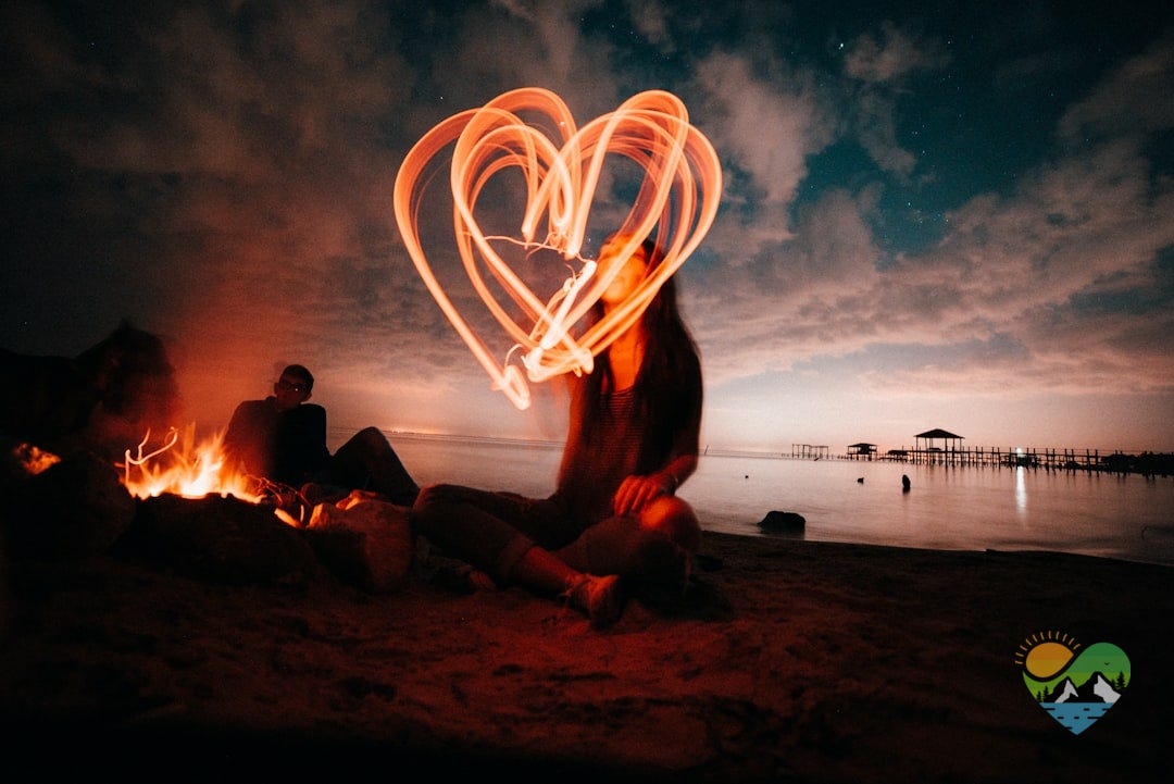 woman sitting on sand near bonfire