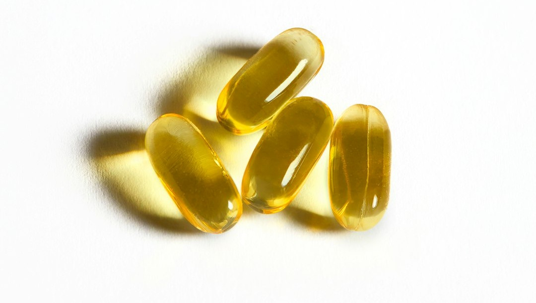 Four yellow capsules sit on a white surface. Four yellow capsules sit on a white surface.