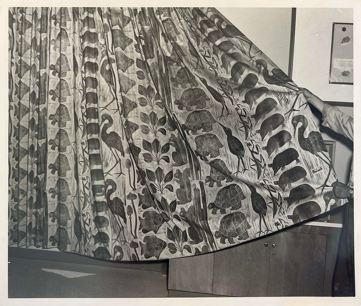 black and white photo of large curtain with many animals printed in. repeated columns