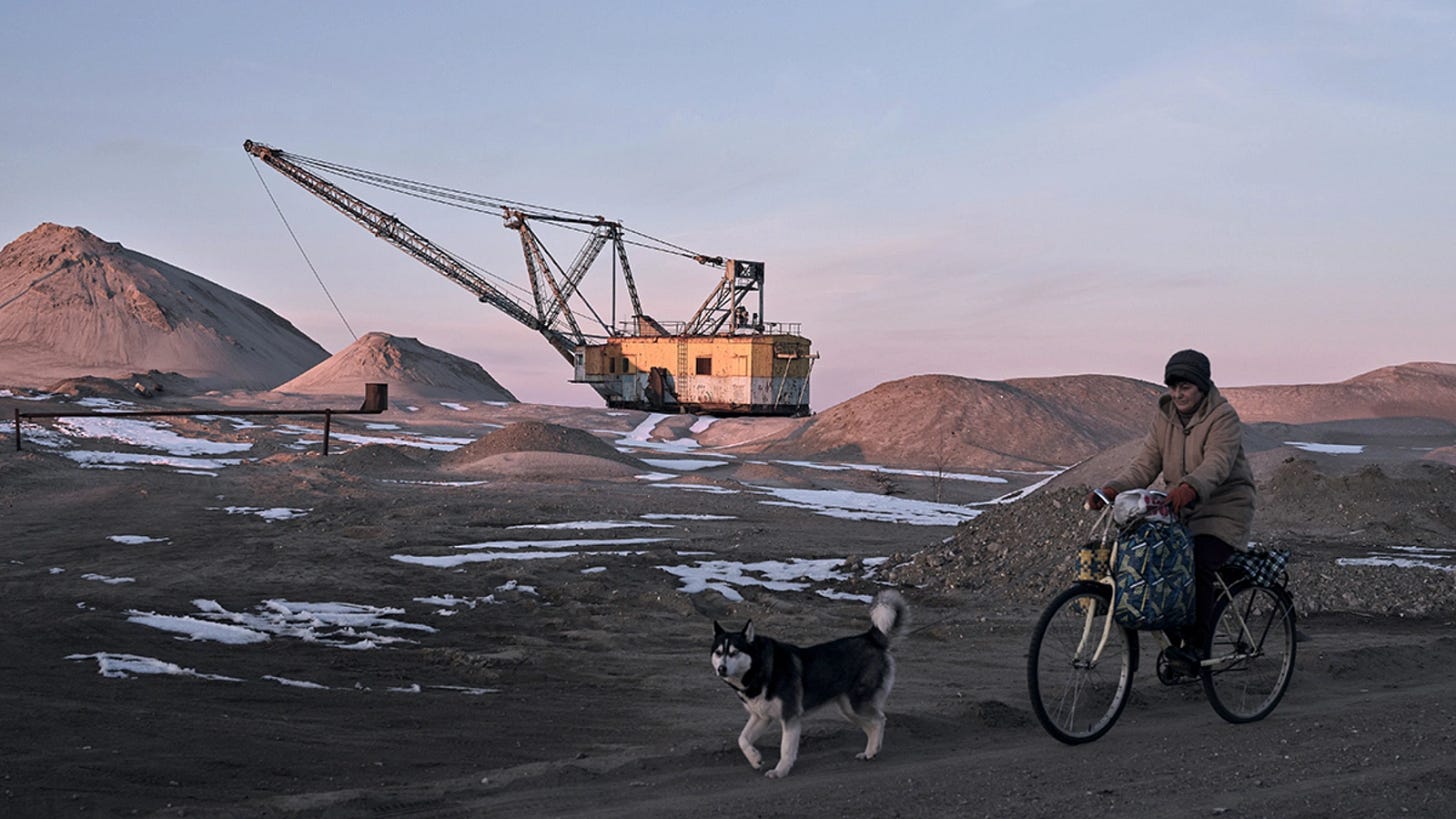 A woman cycles past with her dog as Drag-line excavator mines rare earth materials in Ukraine on February 25, 2025. A woman cycles past with her dog as Drag-line excavator mines rare earth materials in Ukraine on February 25, 2025.