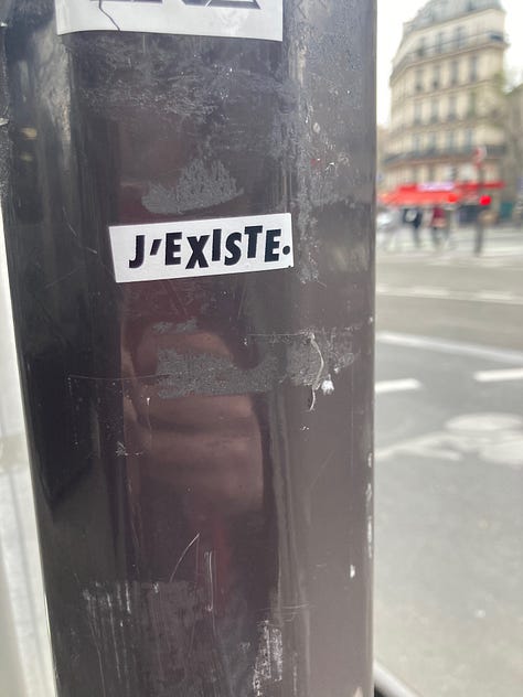 The J'existe sticker in three locations in Paris