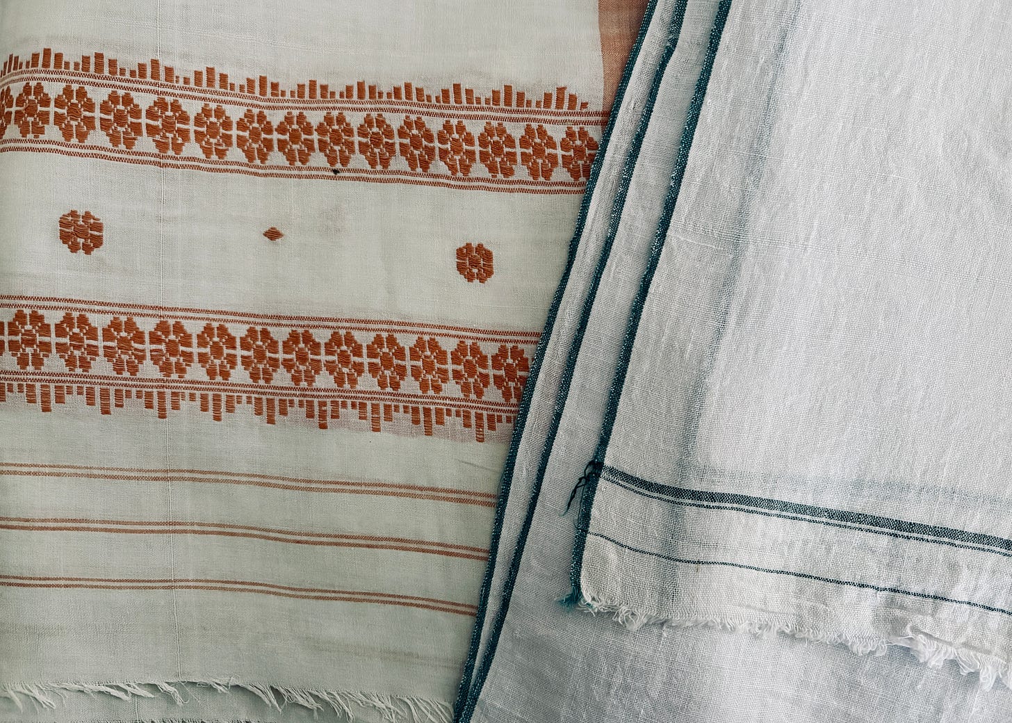 Close-up of a folded cotton sador and khadi dhoti, traditional garments once worn by the author’s late parents, showing the textures and weave of the fabric that reflect everyday life and cultural continuity. Close-up of a folded cotton sador and khadi dhoti, traditional garments once worn by the author’s late parents, showing the textures and weave of the fabric that reflect everyday life and cultural continuity.