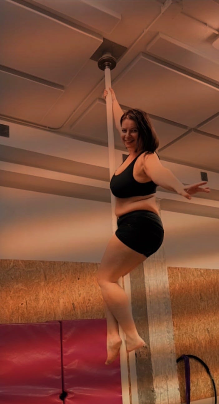 Woman climbing pole dance pole reaching toward ceiling on New Year's Eve at age 46, demonstrating pole fitness achievement in midlife Woman climbing pole dance pole reaching toward ceiling on New Year's Eve at age 46, demonstrating pole fitness achievement in midlife