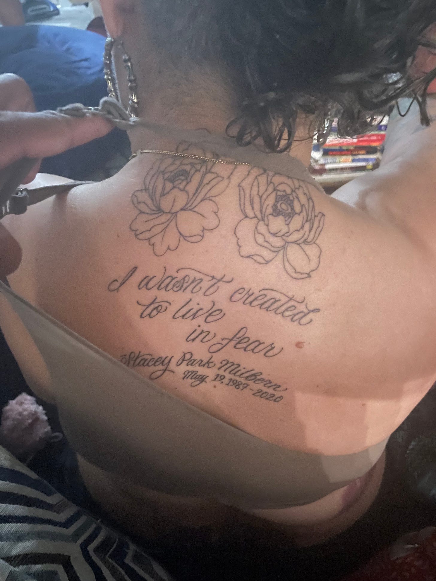 image of Leah's. back with tattoo outline of two peonies and the words I wasnt born to live in fear- Stacy Park Milber May 18, 1983-2020 in script