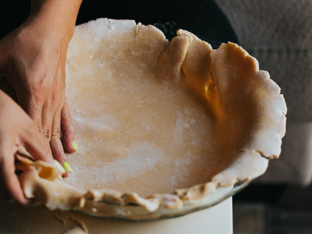 person holding white ceramic bowl with brown and white cake