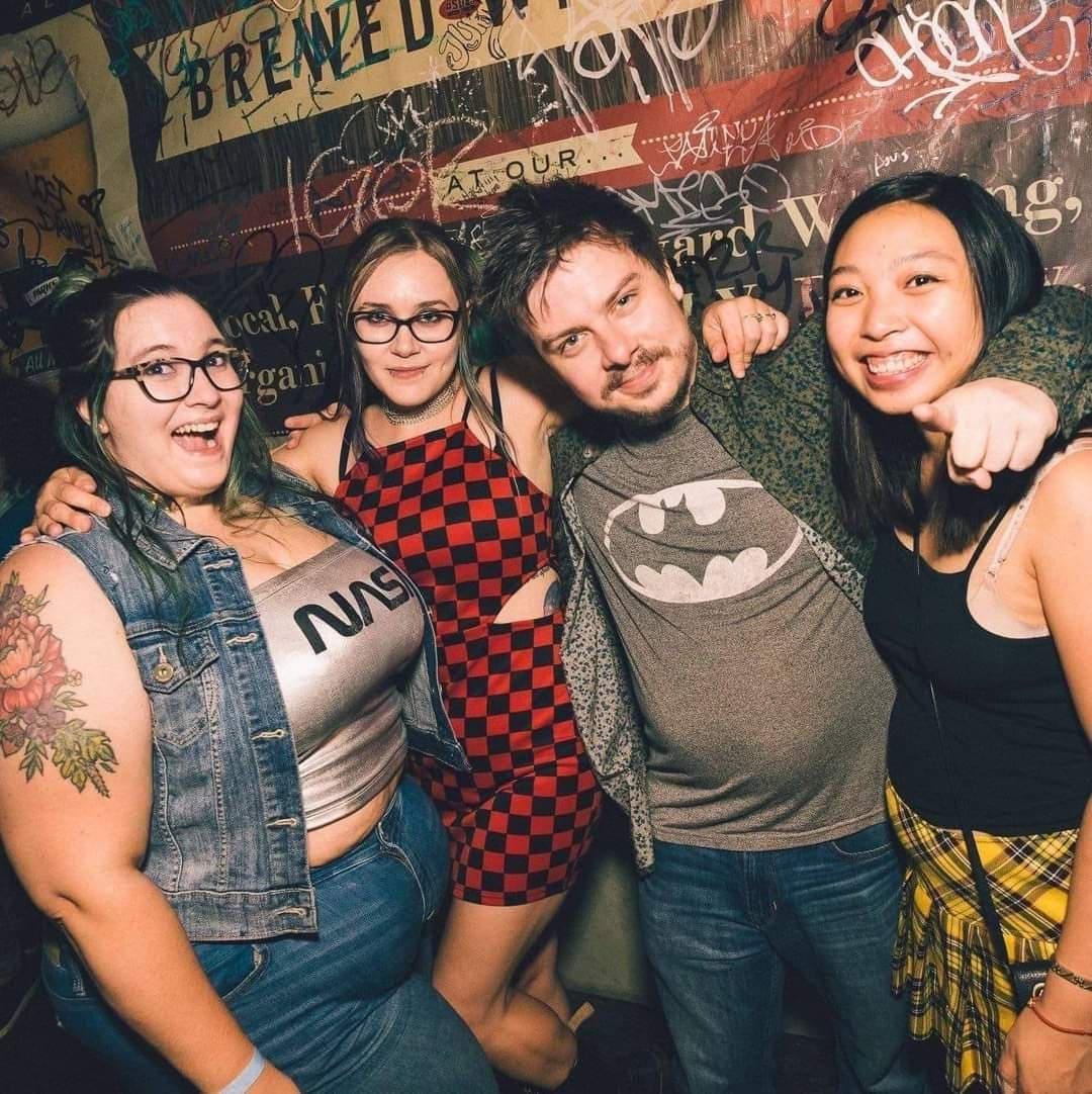 Four teenagers pose in front of Sneaky Dee's mural. Four teenagers pose in front of Sneaky Dee's mural.