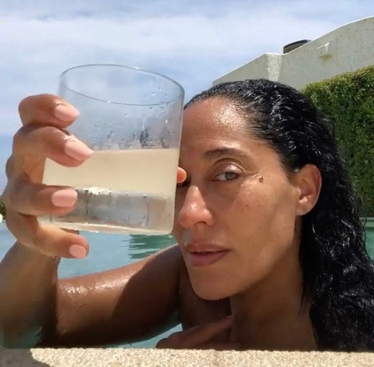 This may contain: a woman holding up a glass of wine in her hand while sitting next to a swimming pool This may contain: a woman holding up a glass of wine in her hand while sitting next to a swimming pool