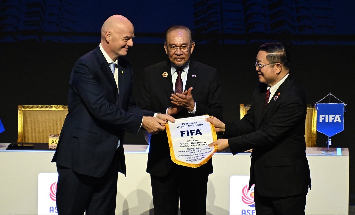 FIFA President Gianni Infantino and ASEAN Secretary-General Dr. Kao Kim Hourn exchange a commemorative pennant during the MoU signing ceremony in Kuala Lumpur, witnessed by Malaysian Prime Minister Anwar Ibrahim. FIFA President Gianni Infantino and ASEAN Secretary-General Dr. Kao Kim Hourn exchange a commemorative pennant during the MoU signing ceremony in Kuala Lumpur, witnessed by Malaysian Prime Minister Anwar Ibrahim.