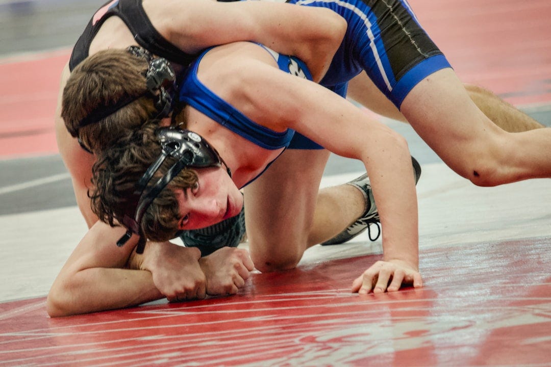 Two wrestlers grappling on a red mat Two wrestlers grappling on a red mat