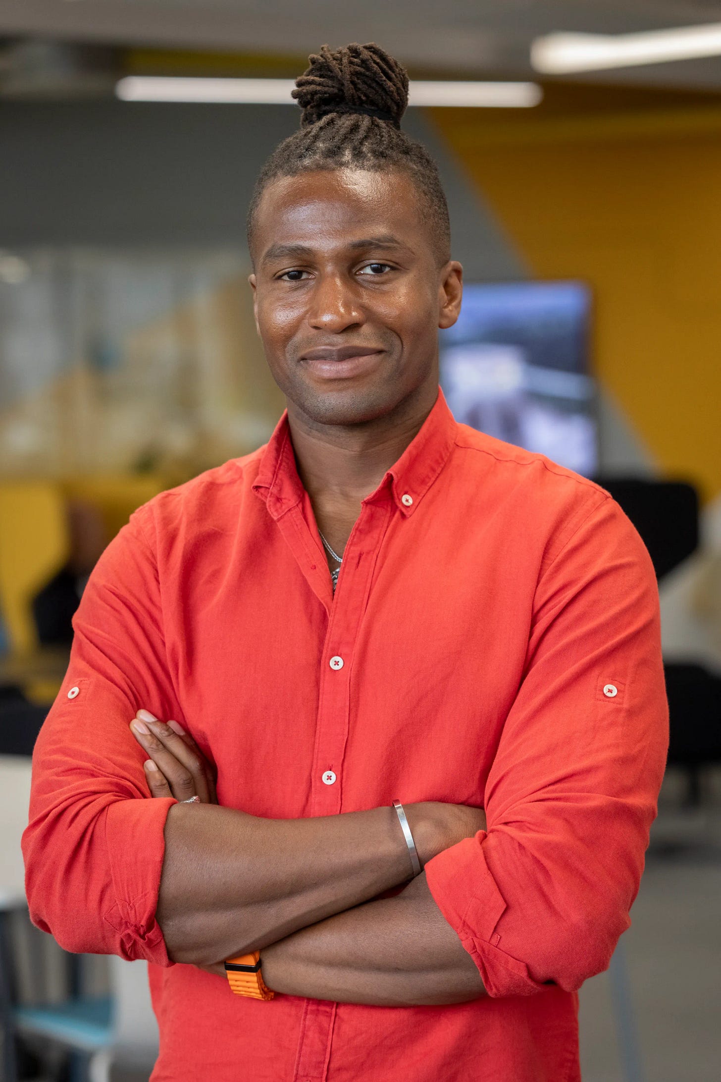 Silas Adekunle, founder of a seven-figure AI platform, smiling with his arms crossed.