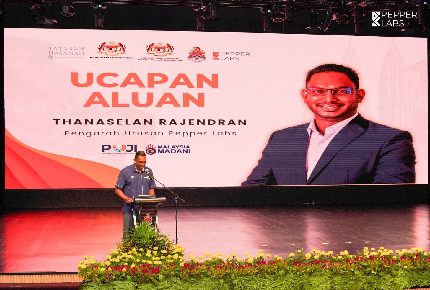 May be an image of ‎2 people, dais and ‎text that says "‎YAVANAN ANAH ኢትበያ ኢይ رلخ EWANGAN WRARTE PEPPER LABS PEPPER LABS UCAPAN ALUAN THANASELAN RAJENDRAN Pengarah Urusan Pepper PengarahUrusanPepperLab PepperLabs Labs PIOJI P MALAYSIA هفجبيد ف MADANI‎"‎‎