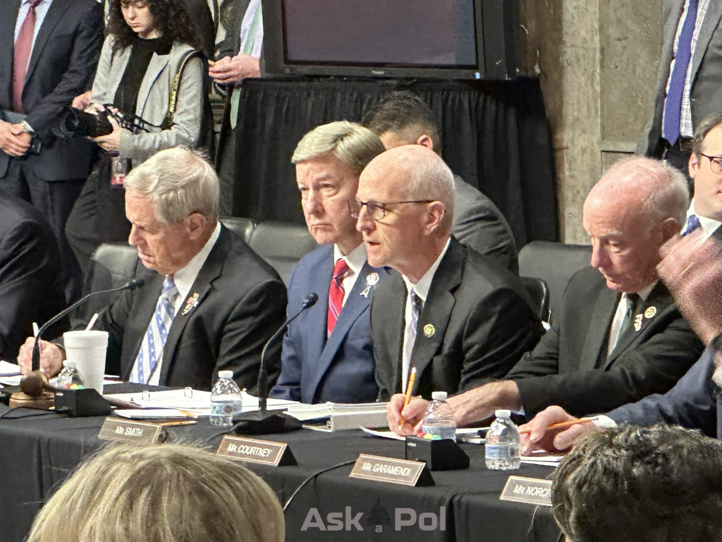 Man in suit speaks from dais as other men in suits take notes Photo: Matt Laslo ™ www.askapol.com