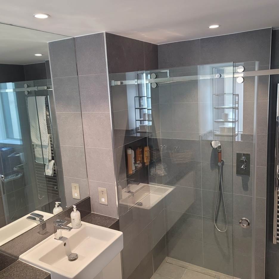 A bathroom with a glass shower and sink

AI-generated content may be incorrect.