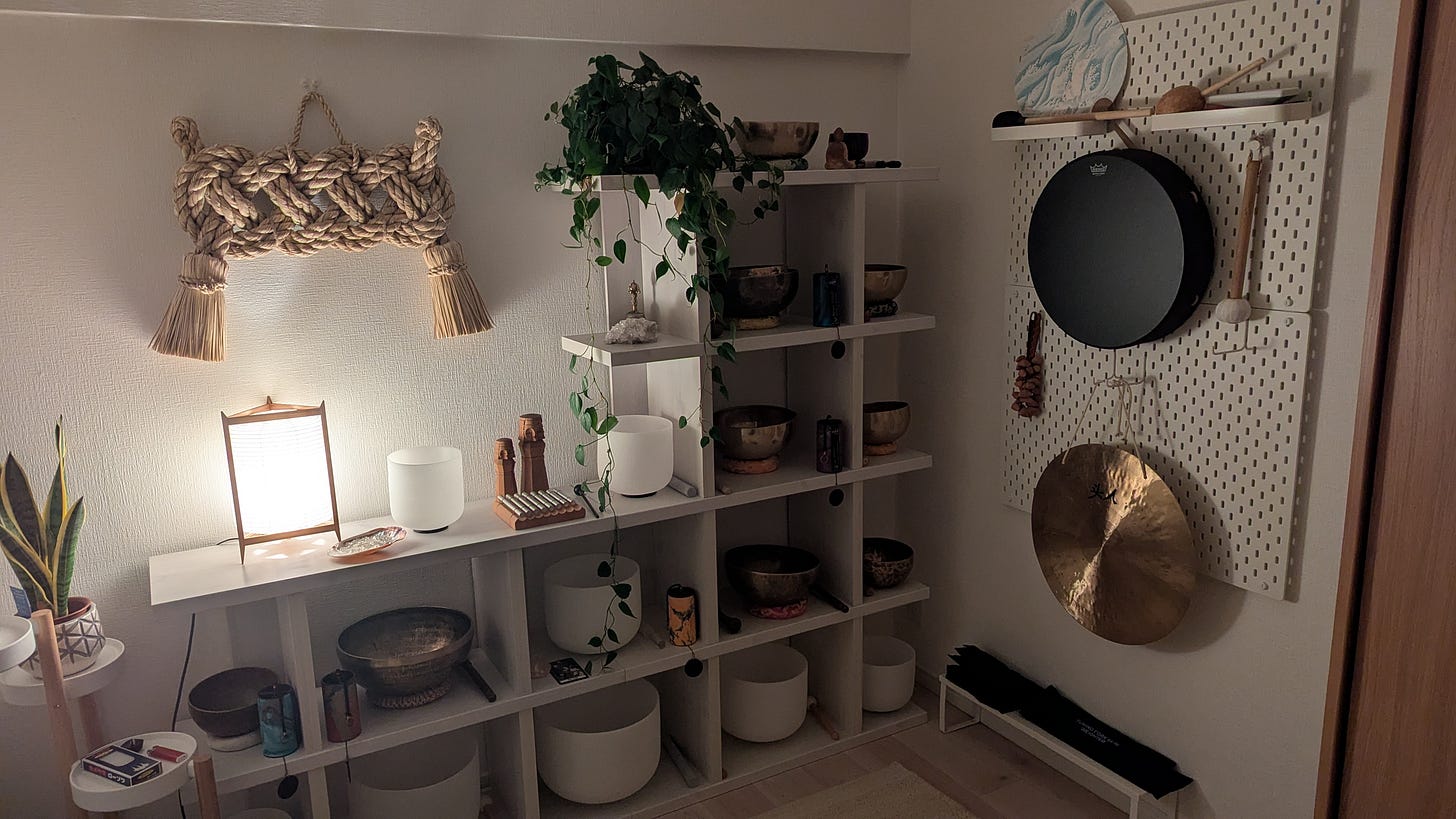 A calm corner space with a soft-lit lantern casts a glow on shelves of sound healing instruments, including crystal and Tibetan singing bowls.