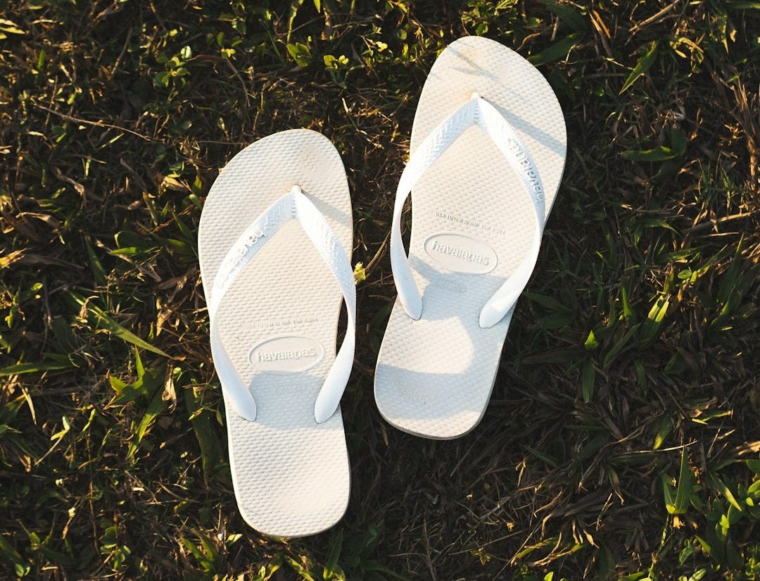 a pair of white slippers sitting on top of a lush green field