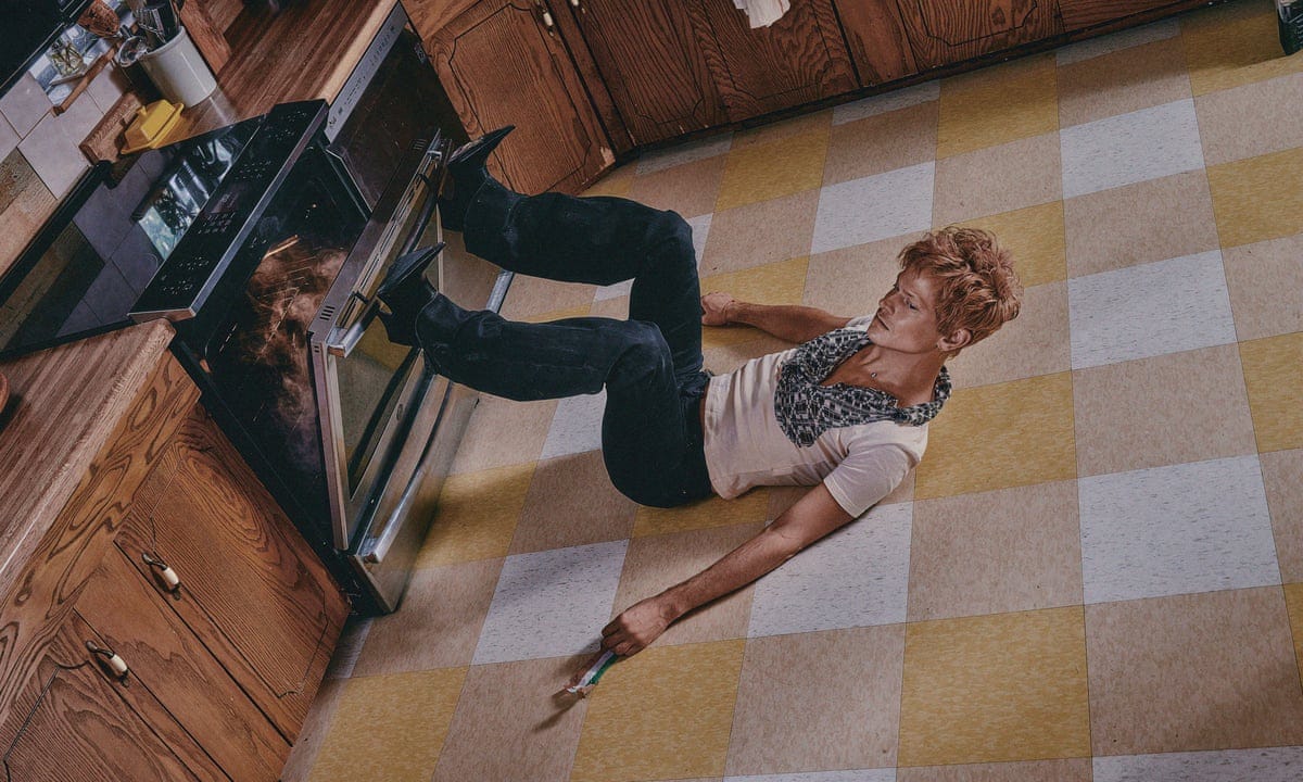 Off-putting promo pic for "Glory," featuring Perfume Genius opening a smoking oven with high heels while laying on his back on the kitchen floor.